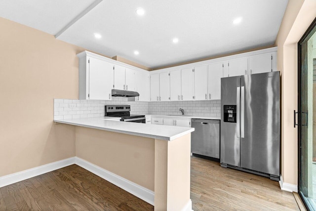 kitchen featuring kitchen peninsula, tasteful backsplash, stainless steel appliances, light hardwood / wood-style flooring, and white cabinetry