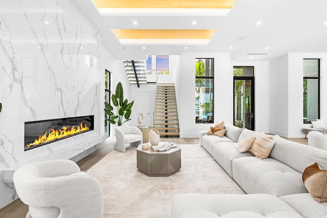 living room with a fireplace, plenty of natural light, light hardwood / wood-style floors, and a tray ceiling