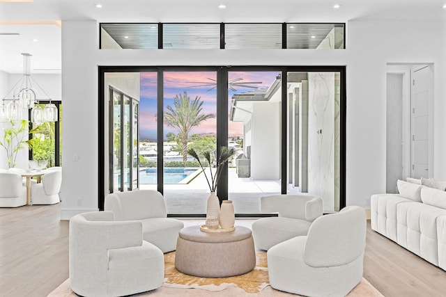 living room featuring a wealth of natural light, light hardwood / wood-style flooring, and an inviting chandelier