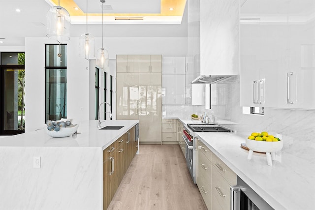 kitchen with light hardwood / wood-style floors, double oven range, sink, white cabinetry, and decorative light fixtures