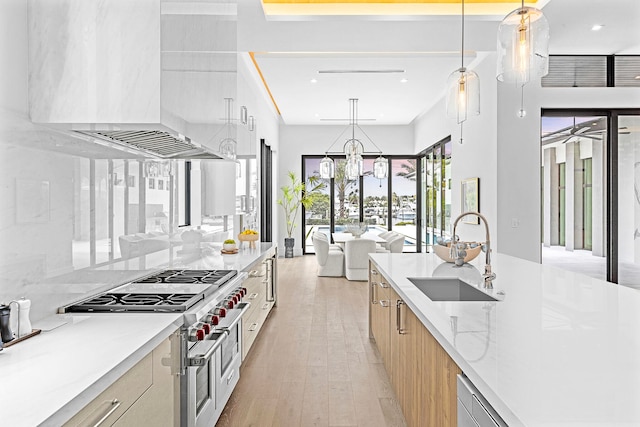 kitchen with double oven range, sink, decorative light fixtures, and light stone counters