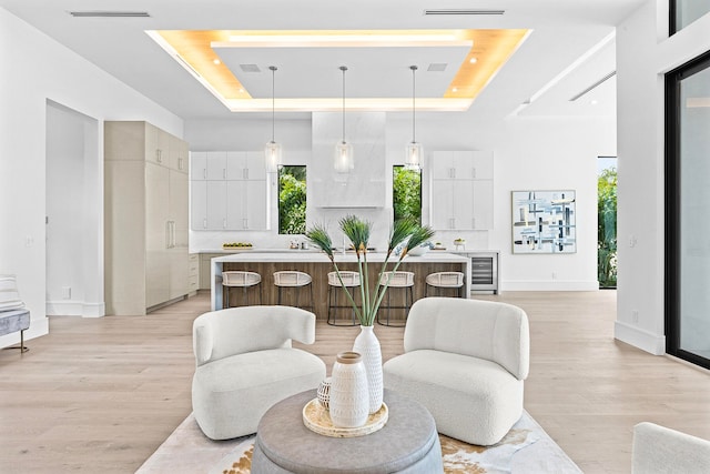 interior space featuring light hardwood / wood-style floors, a tray ceiling, and wine cooler