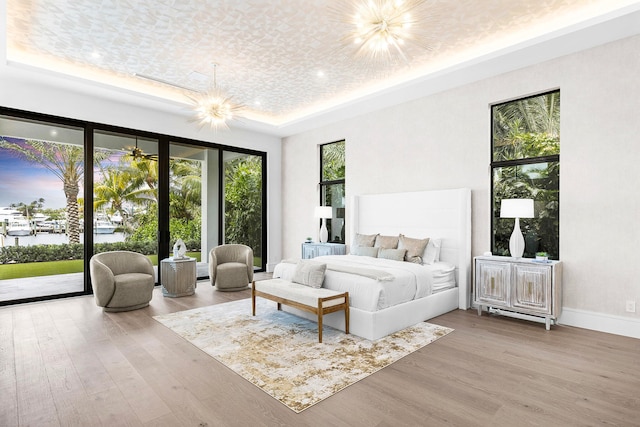 bedroom with access to outside, a chandelier, wood-type flooring, and multiple windows