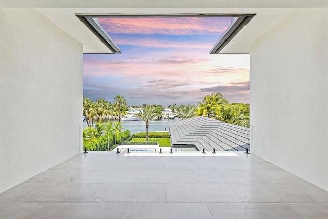 balcony at dusk with a water view and a patio area