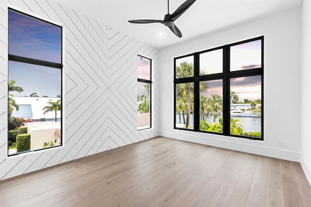 unfurnished room featuring light hardwood / wood-style flooring, a water view, and ceiling fan