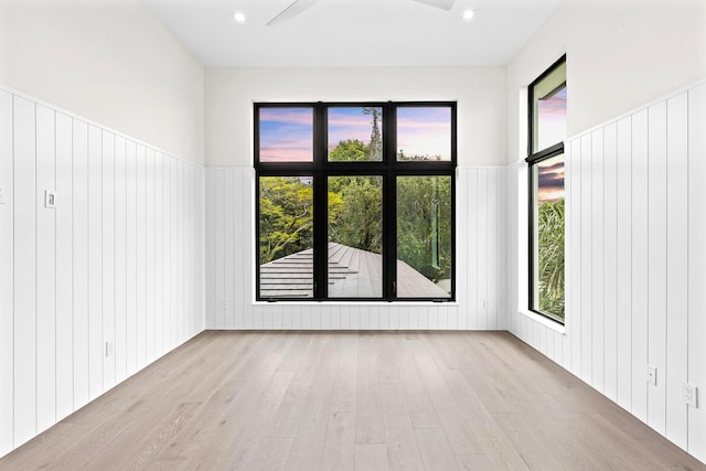 unfurnished room featuring light hardwood / wood-style floors and wooden walls