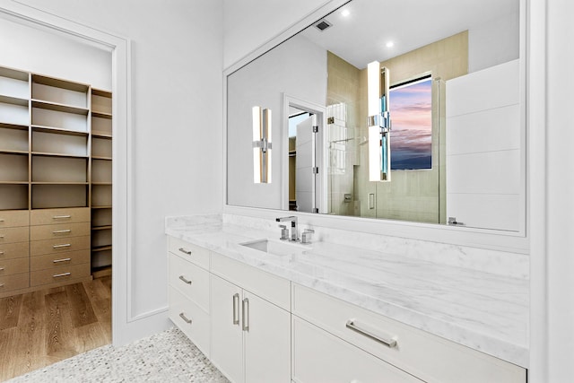 bathroom with wood-type flooring, vanity, and a shower with door