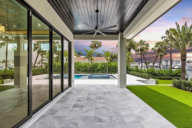 patio terrace at dusk featuring a swimming pool with hot tub, a yard, and ceiling fan