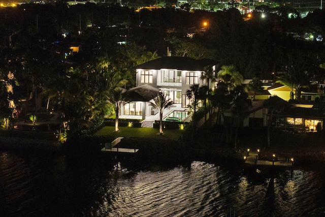 back house at night with a patio and a water view