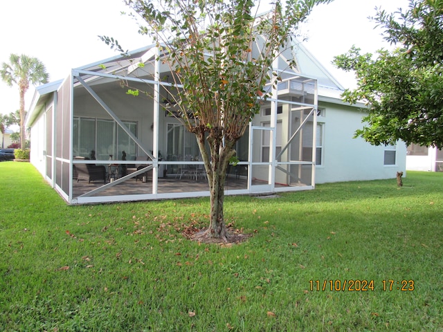 back of house featuring glass enclosure and a lawn