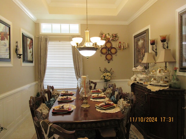 dining area with a notable chandelier, a raised ceiling, and crown molding