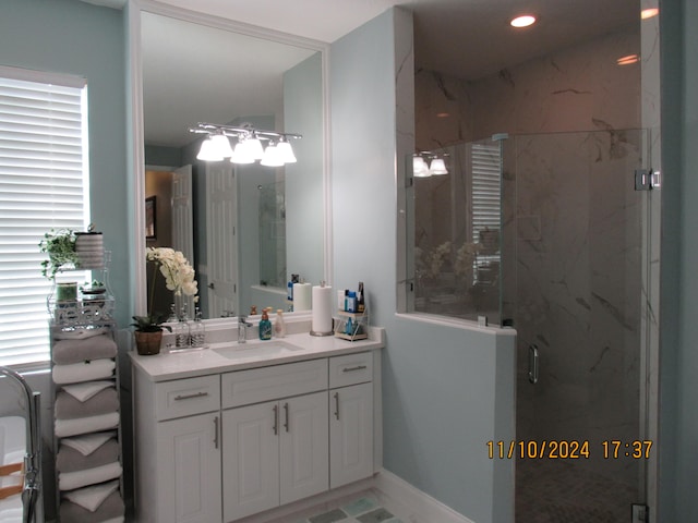 bathroom featuring vanity, a healthy amount of sunlight, and a shower with shower door