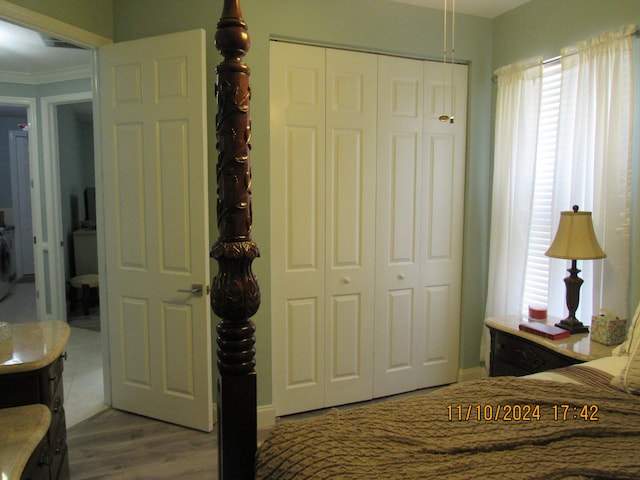 bedroom featuring hardwood / wood-style floors, multiple windows, crown molding, and a closet