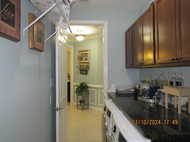 clothes washing area featuring cabinets, light tile patterned flooring, washer and dryer, and ornamental molding