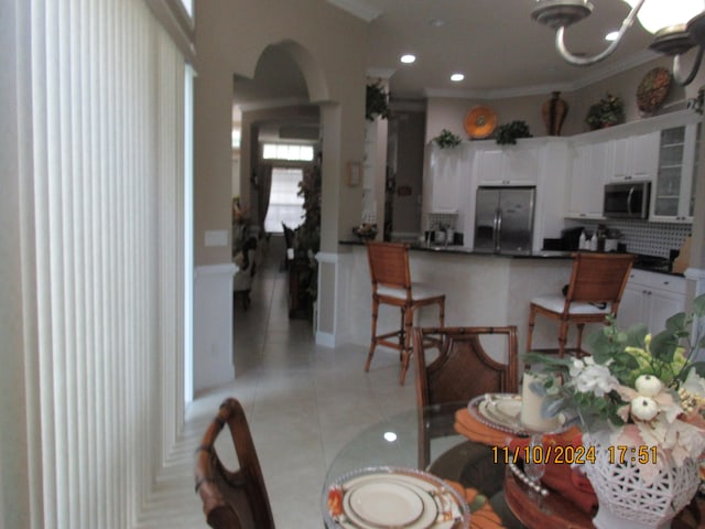 tiled dining space featuring an inviting chandelier and ornamental molding