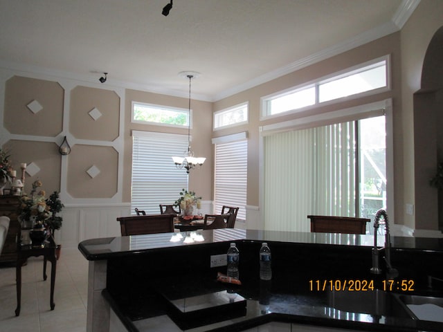 dining area with a chandelier, light tile patterned floors, and ornamental molding