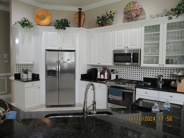 kitchen with white cabinetry, stainless steel appliances, ornamental molding, and backsplash