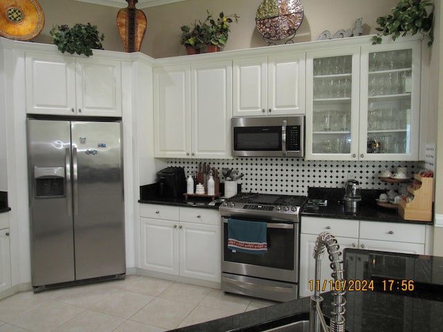 kitchen featuring stainless steel appliances, white cabinets, light tile patterned floors, and decorative backsplash