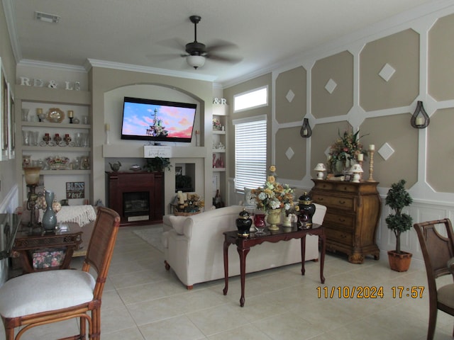 tiled living room featuring ceiling fan, built in features, and crown molding