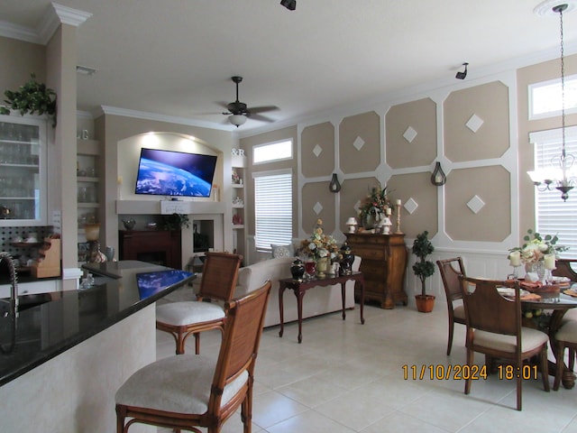 dining area with ornamental molding, ceiling fan with notable chandelier, built in shelves, and a healthy amount of sunlight