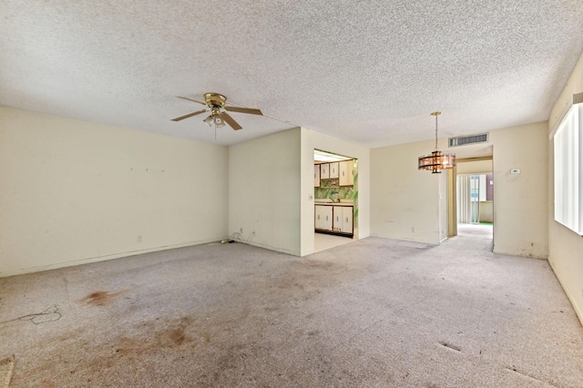 unfurnished living room featuring ceiling fan with notable chandelier, light colored carpet, and a textured ceiling