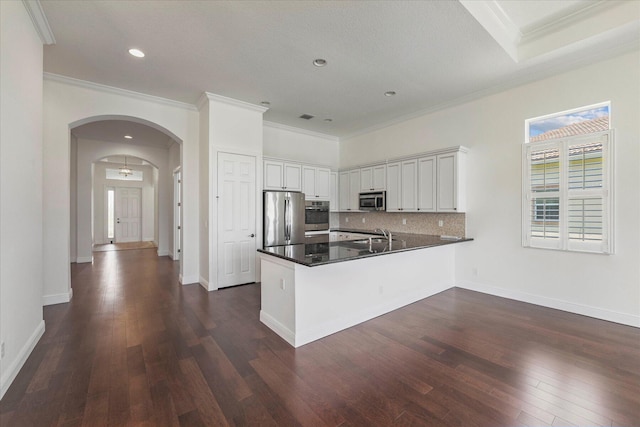 kitchen with stainless steel appliances, dark hardwood / wood-style floors, crown molding, backsplash, and white cabinetry