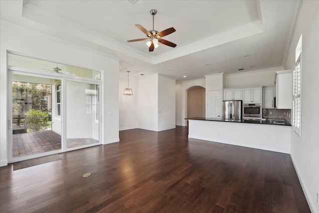 unfurnished living room with dark hardwood / wood-style flooring, a tray ceiling, and crown molding