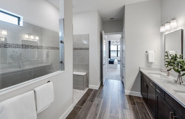 bathroom with a wealth of natural light, ensuite bath, wood finish floors, and a sink