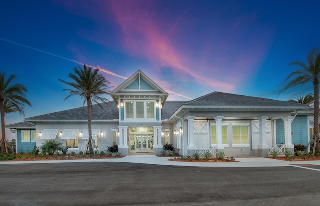 front of property at dusk featuring french doors and stucco siding