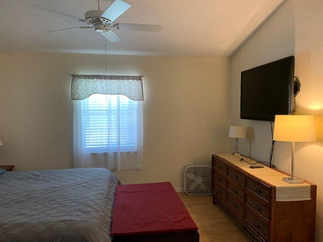 bedroom featuring hardwood / wood-style flooring, ceiling fan, a textured ceiling, and lofted ceiling