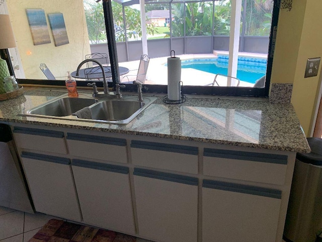 kitchen with white cabinets, sink, and light stone counters