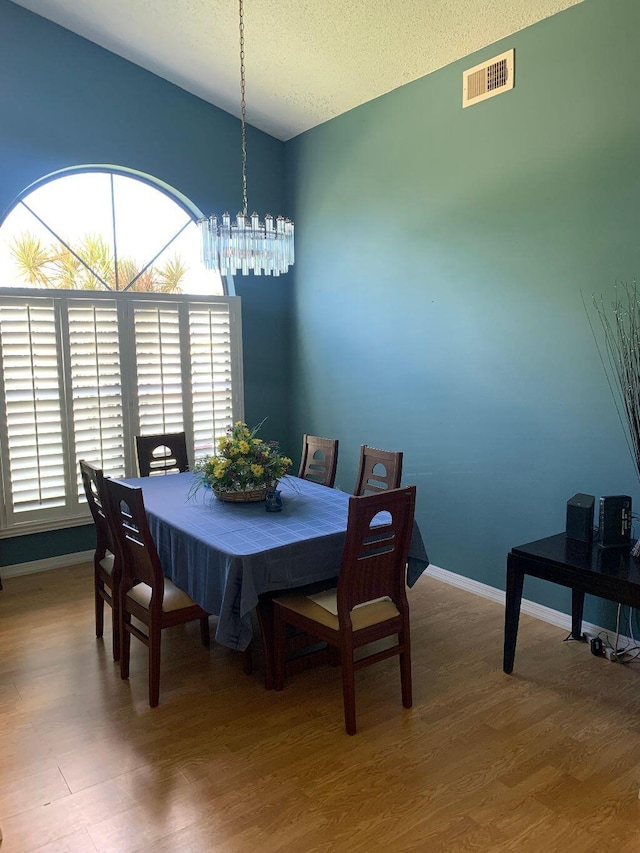 dining space featuring hardwood / wood-style floors, a textured ceiling, and an inviting chandelier