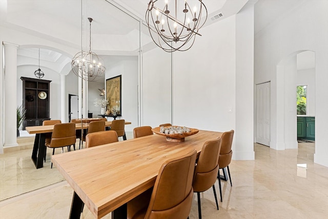 dining room with an inviting chandelier, a towering ceiling, ornamental molding, a tray ceiling, and decorative columns