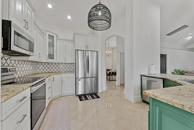 kitchen with decorative backsplash, appliances with stainless steel finishes, light stone counters, decorative light fixtures, and white cabinets