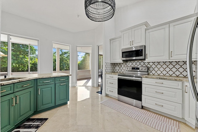 kitchen featuring backsplash, white cabinets, green cabinets, light stone countertops, and stainless steel appliances