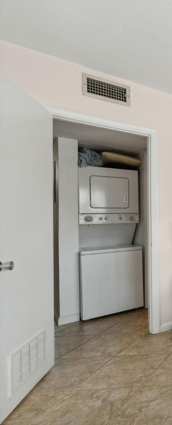 washroom with stacked washing maching and dryer and a textured ceiling