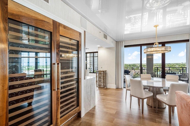 dining space with hardwood / wood-style floors, a towering ceiling, and an inviting chandelier