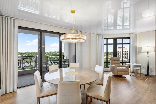 dining space featuring a high ceiling, light hardwood / wood-style floors, and a notable chandelier