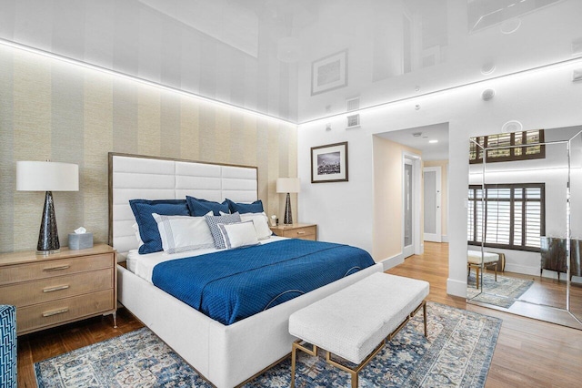 bedroom with hardwood / wood-style floors and a towering ceiling