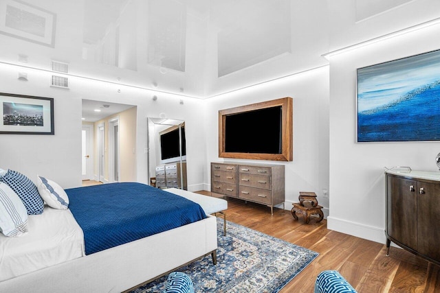 bedroom with a high ceiling and hardwood / wood-style flooring