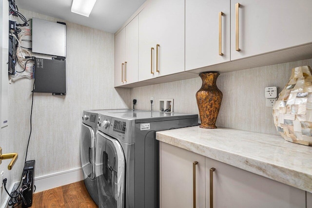 laundry room featuring cabinets, dark wood-type flooring, and washing machine and clothes dryer