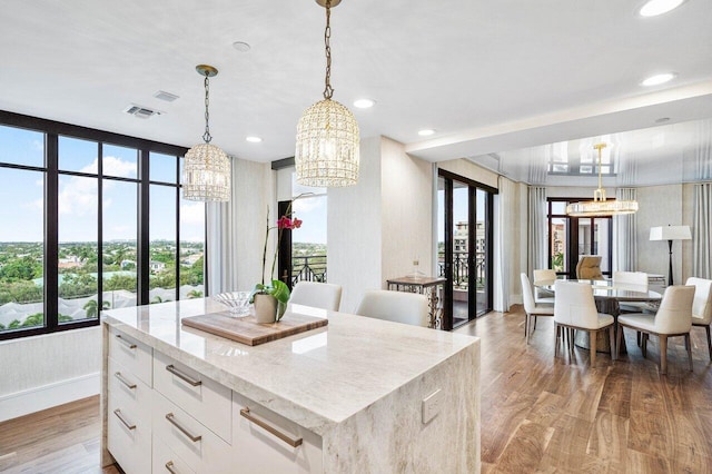 kitchen featuring a center island, white cabinets, hanging light fixtures, and light wood-type flooring