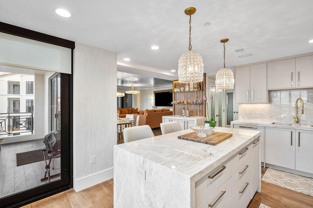 kitchen featuring white cabinetry, sink, light hardwood / wood-style flooring, decorative backsplash, and a kitchen island