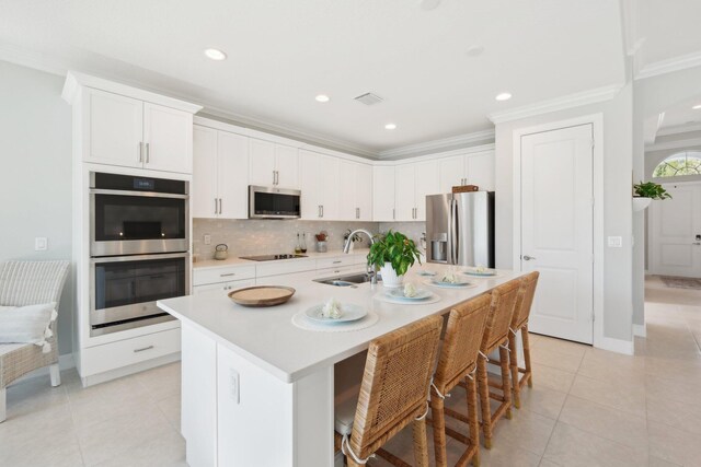 kitchen featuring a breakfast bar area, a kitchen island with sink, and appliances with stainless steel finishes