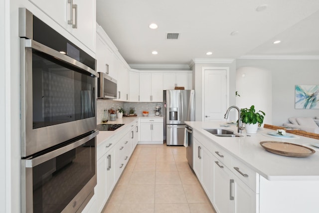 kitchen with visible vents, stainless steel appliances, a sink, light countertops, and tasteful backsplash