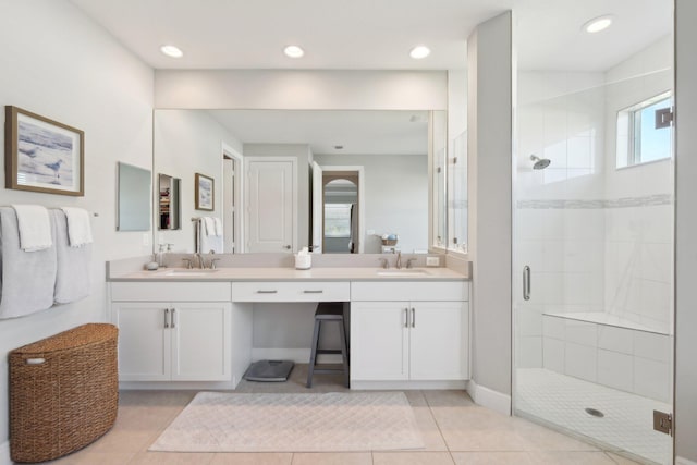 bathroom featuring tile patterned flooring, a stall shower, double vanity, and a sink