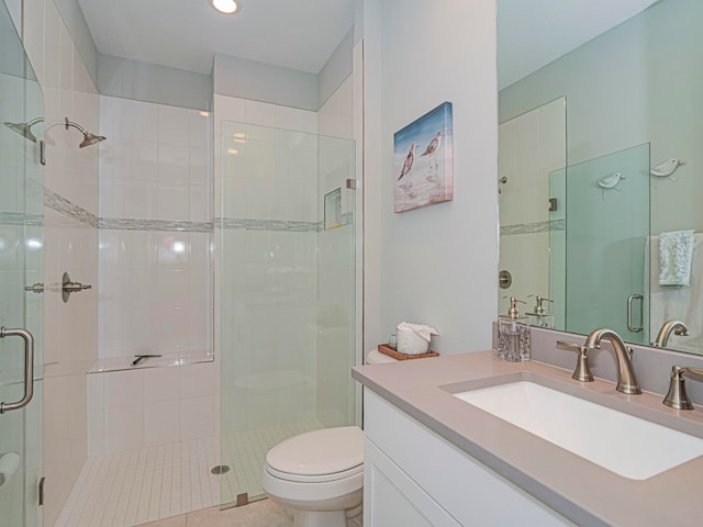 bathroom with toilet, vanity, tile patterned floors, and a shower with shower door