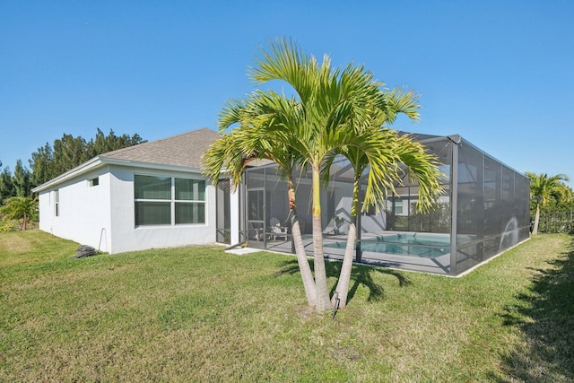 back of property with an outdoor pool, stucco siding, a yard, and a lanai