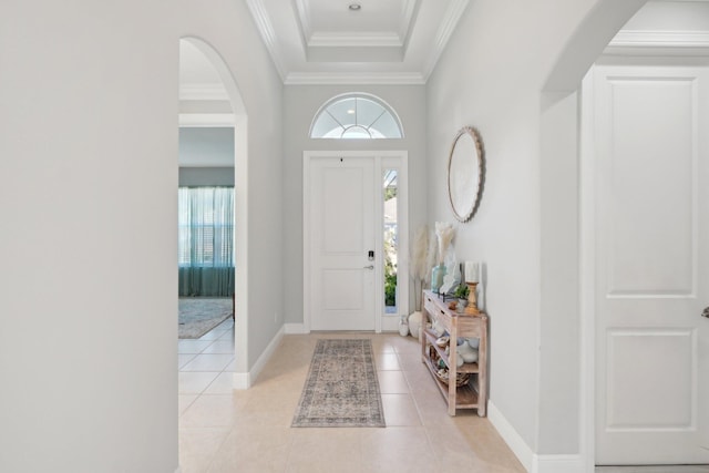 foyer featuring light tile patterned floors, baseboards, arched walkways, and crown molding