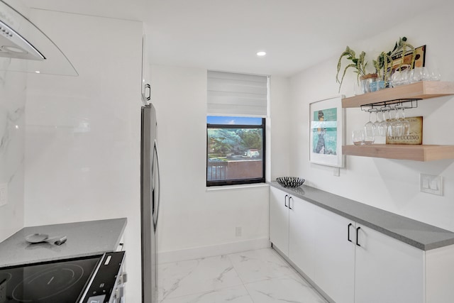 kitchen with stainless steel fridge, white cabinets, and range